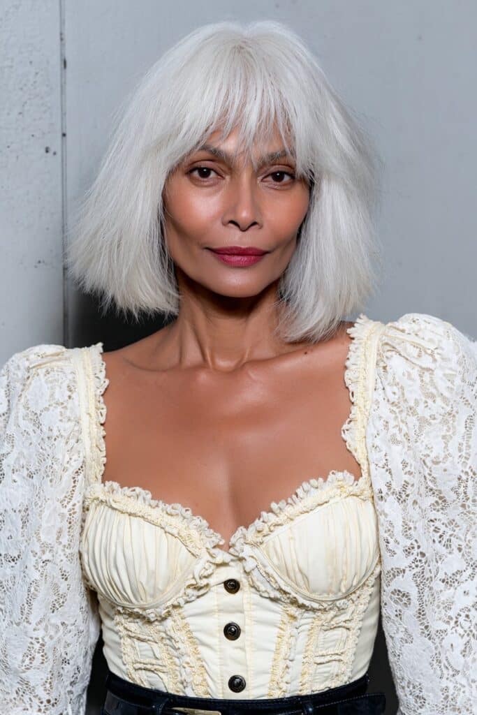 Ash blonde shaggy wolf cut for woman over 50 with choppy layers and full fringe.