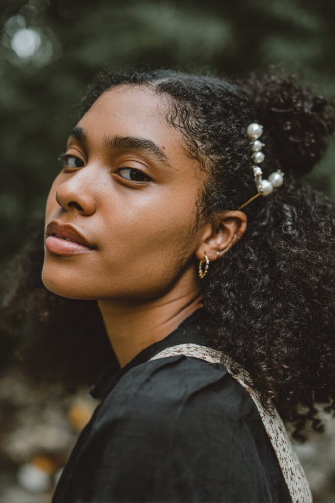 Elegant American woman over 12 with vintage-inspired rolled updo, urban brick wall backdrop, soft lighting, Instagram-style.