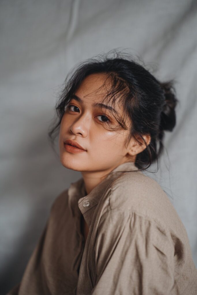 Elegant American woman over 12 with elegant chignon and hair vine, soft gray fabric backdrop, natural lighting, Instagram-style.