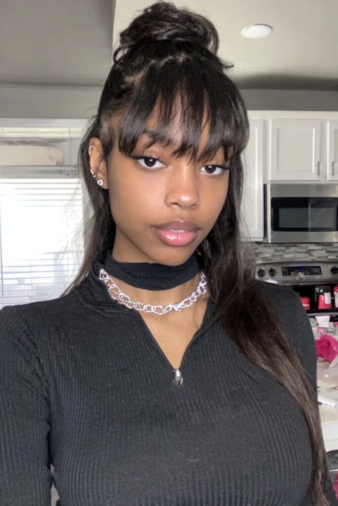 17 Stunning Half Up Half Down Quick Weave Hairstyles 3 A woman with a half up half down quick weave styled with soft bangs and smooth layers.