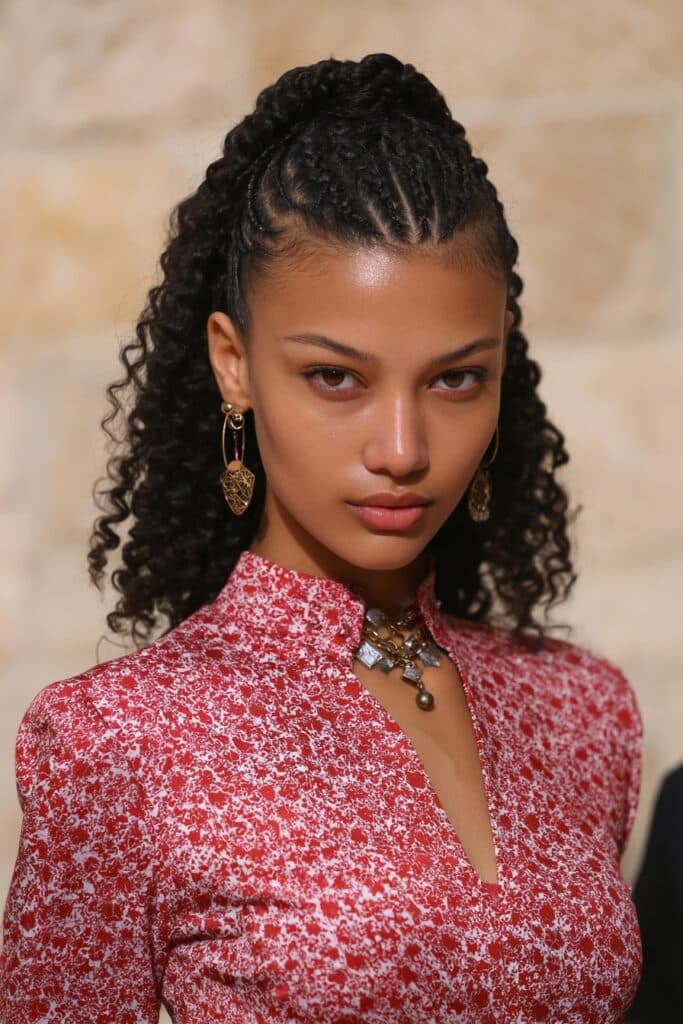 Girl with knotless braids styled into two low buns and curls