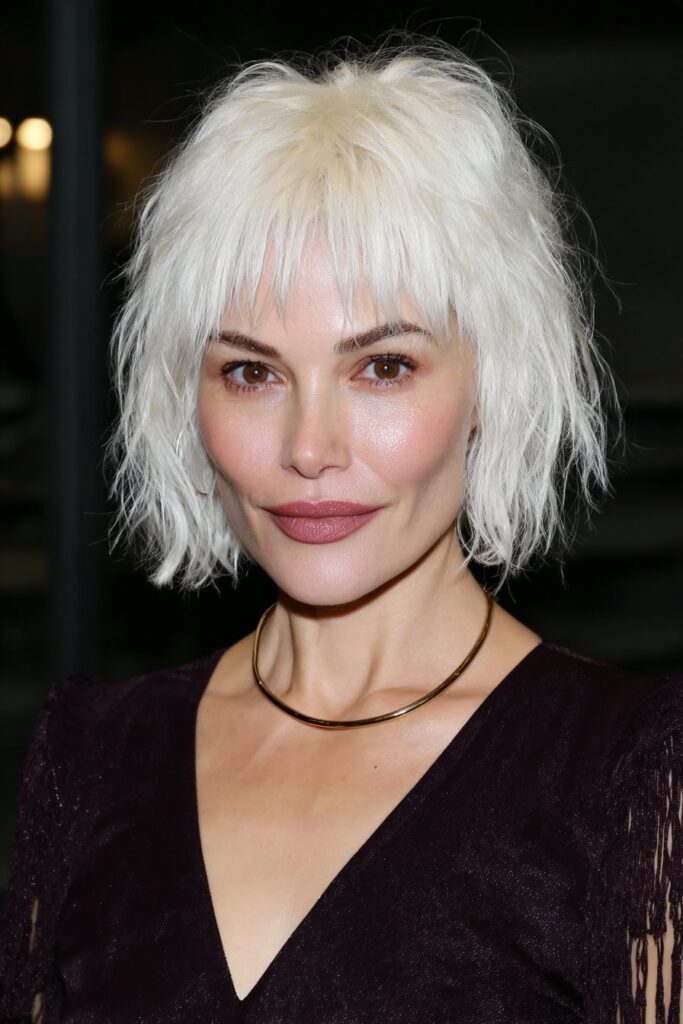 Trendy silver short shaggy pixie haircut for woman over 50 with textured layers and wispy bangs.