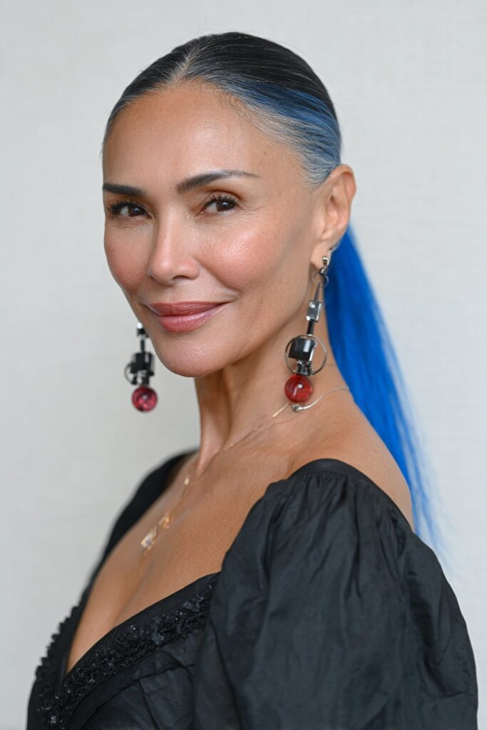 Stylish 60-year-old woman with a butterfly haircut featuring a bright money piece framing her face.