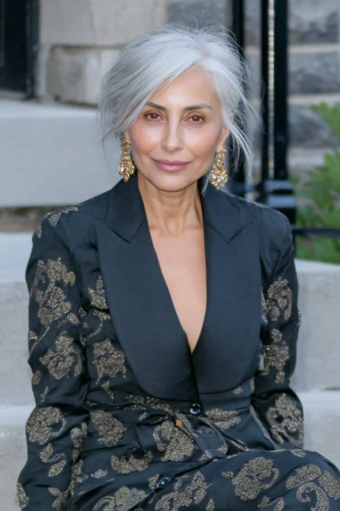 Graceful 60-year-old woman with a butterfly haircut and subtle highlights that brighten her layered hair.