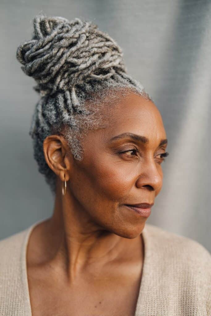 Braids gathered into a high bun with loose curls cascading for added texture and softness.