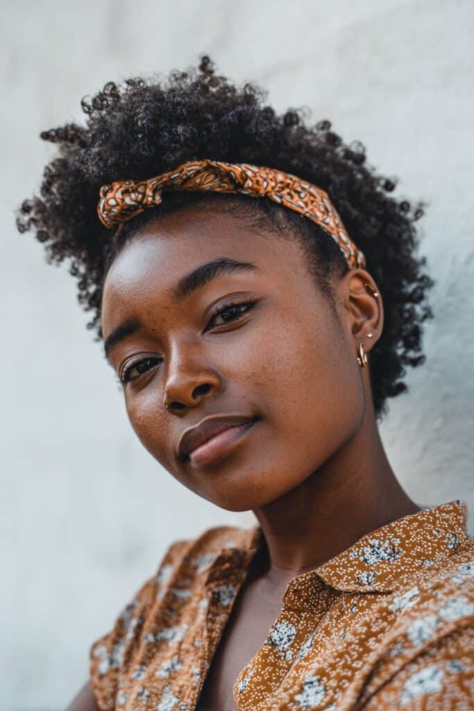 Curly hair gathered high and positioned to one side for a lifted, playful pineapple look.