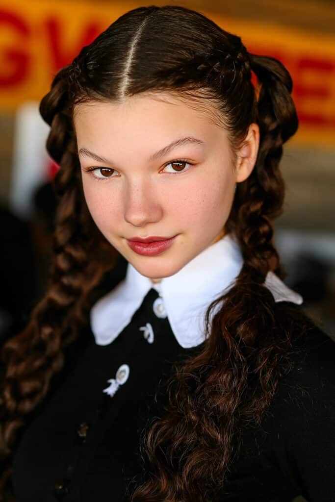 School girl with a neat braided headband style, keeping curls off her face for a clean classroom look.