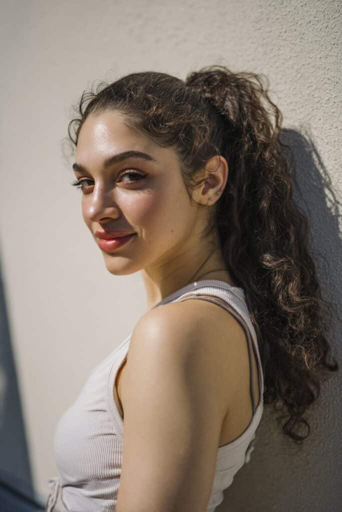 A curly ponytail styled with lifted volume at the crown for extra height and bounce.