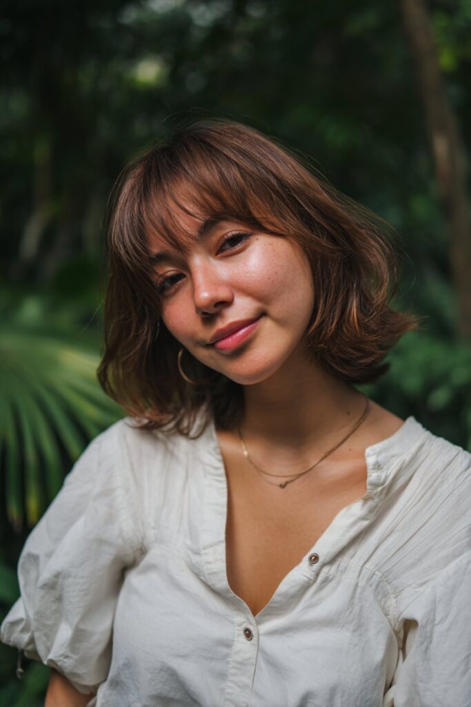 Gentle butterfly layers paired with long, eye-grazing bangs for a soft, flattering look.