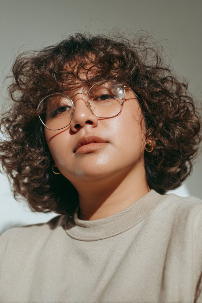 Curly bob hairstyle with face-framing layers for women.