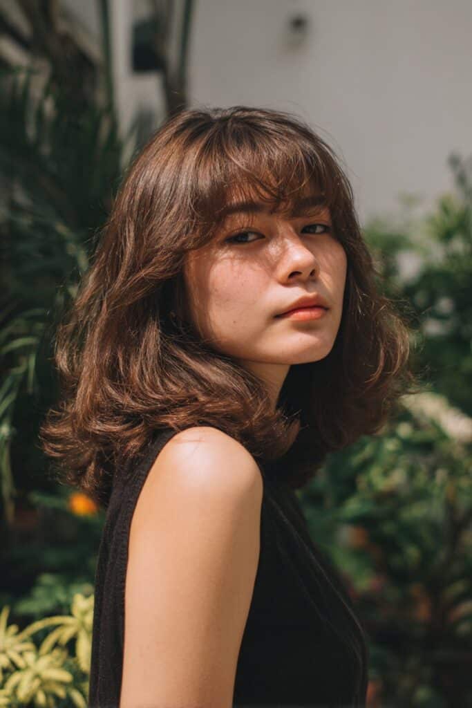 Straight hair with curtain bangs styled with side part and loose waves