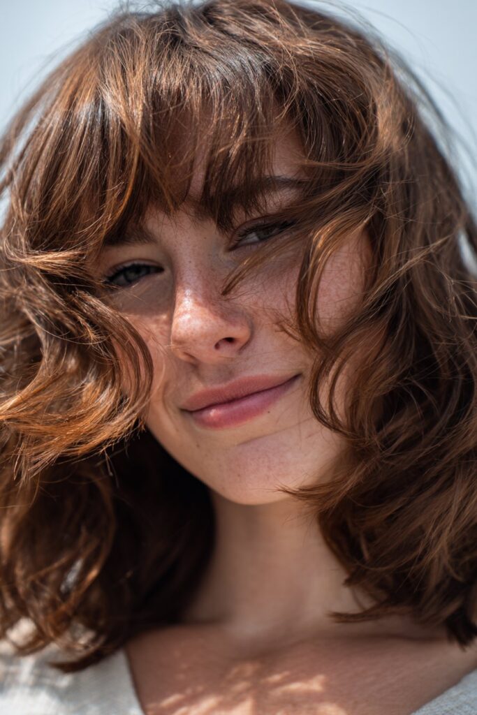 Tousled wavy medium haircut with curtain bangs