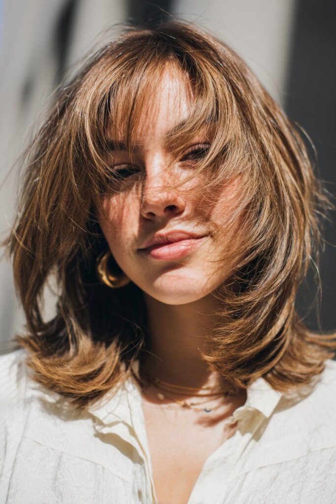 Wispy shoulder-length haircut with layered curtain bangs